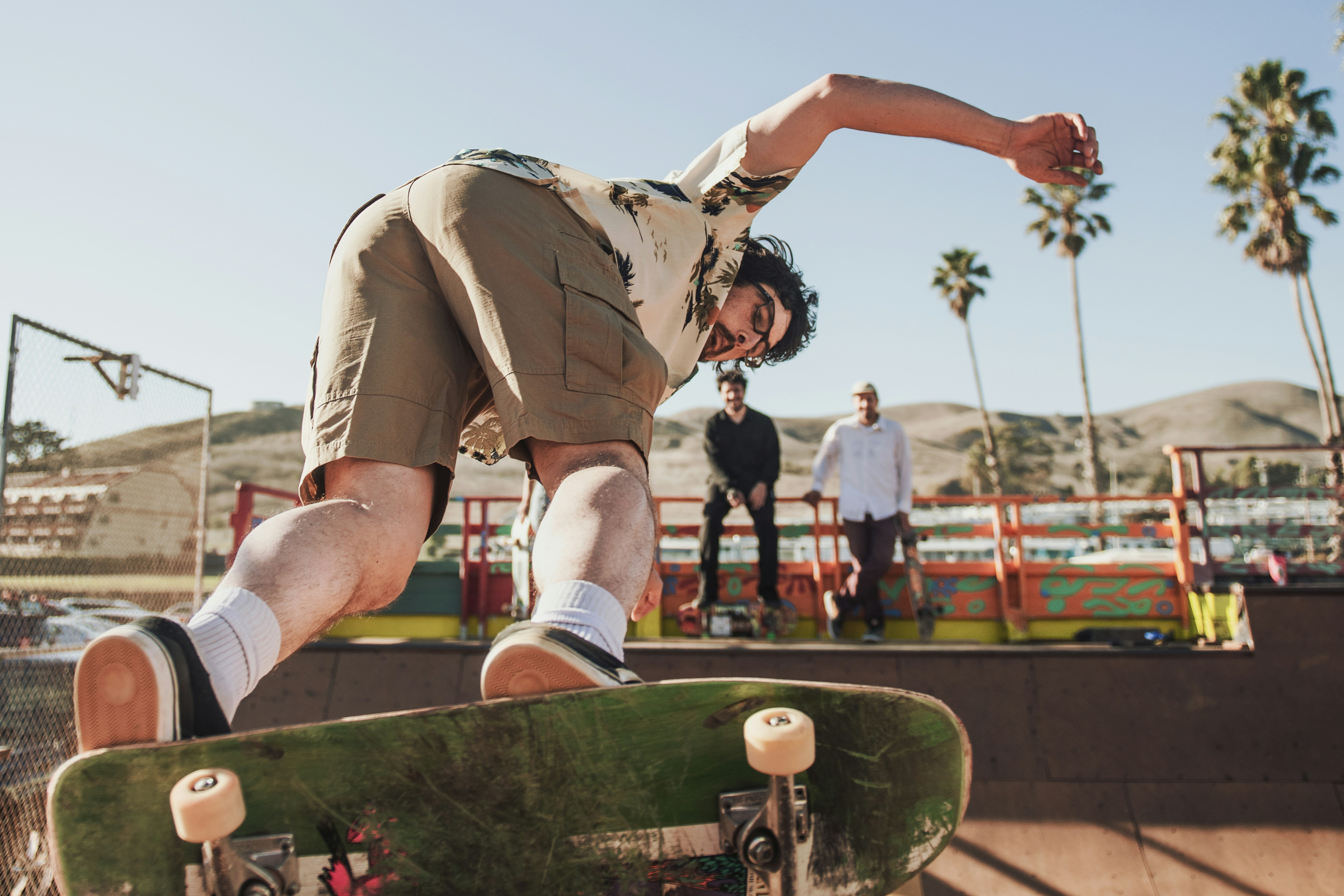 man in green camouflage shirt and brown shorts jumping on brown wooden fence during daytime